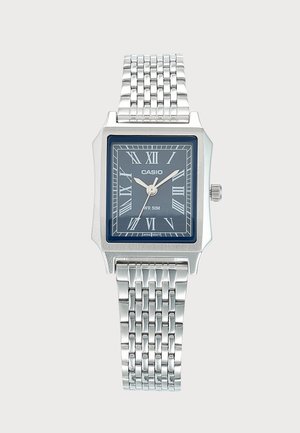 Sølv Casio armbåndsur med rektangulært blåt urværk, romertal, tre viser og ledet metalrem.