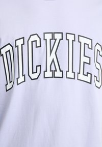 Světle fialové tričko s výrazným černým textem "DICKIES." Vyrobené z měkké tkaniny s kulatým výstřihem a krátkými rukávy. Jednoduchý design.