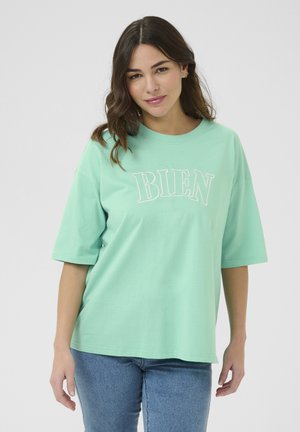 T-shirt en coton vert menthe, à manches courtes, arborant le mot "BIEN" en broderie blanche sur la poitrine. Coupe décontractée.