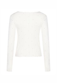 Λευκό τοπ με μακριά μανίκια και ριμπ υφή, διακοσμημένο με μικρά ροζ καρδιάκια σε όλο το ύφασμα και με επάλληλο τελείωμα στο κάτω μέρος.