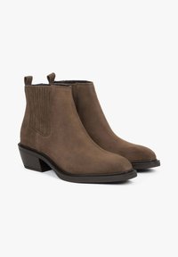 Brązowe botki zamszowe z gładkim wykończeniem, elastycznymi panelami po bokach, pętelkami do ściągania oraz niskim, warstwowym obcasem. Prosty nosek i teksturowana podeszwa.