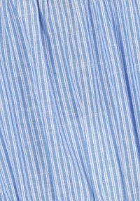 Tissu rayé avec des lignes verticales bleues et blanches, présentant une surface douce et texturée ainsi qu'un matériau léger, idéal pour diverses applications vestimentaires.