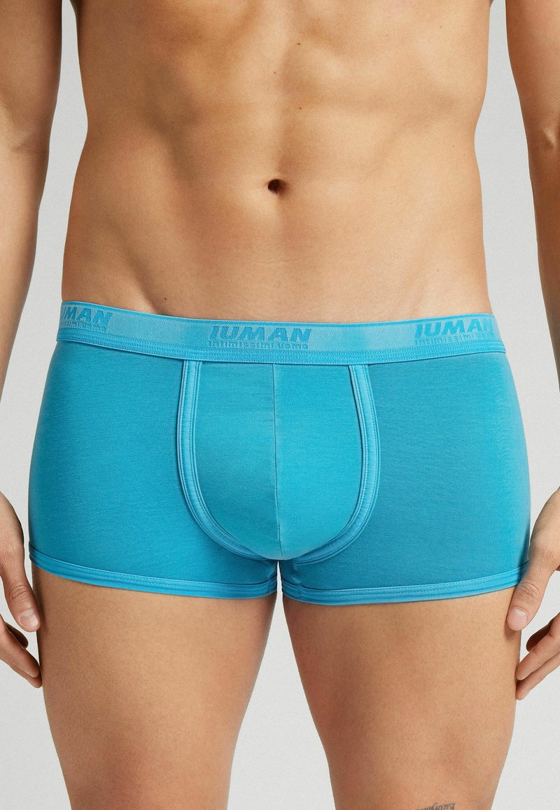 Blå bomullshorts med en tight passform, med en mjuk elastisk midjeband med varumärke. Slät textur, midjehöjd till låret, och en formad ficks design.
