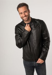 Giubbotto in pelle nera con colletto alto, chiusura frontale con zip e tasche con zip. Tessuto liscia, design aderente e stile minimalista.
