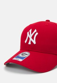 Rote Baseballmütze aus Stoff, mit einem weißen, gestickten NY-Logo, strukturiertem Vorderteil und einem Etikett mit blauen und weißen Akzenten.