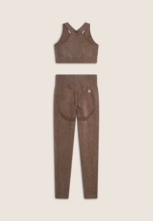 Set di activewear marrone composto da un reggiseno a coste con design a incrocio sulla schiena e pantaloni lunghi con finitura testurizzata e cuciture decorative.