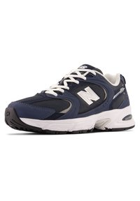 Scarpe da atletica navy con tomaia in mesh e sintetico, lacci bianchi, dettagli grigi e robusta suola in gomma nera. Notevole logo "N" sul lato.