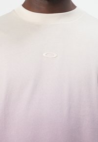T-Shirt mit helllila Farbverlauf, Baumwollmischung, Rundhalsausschnitt, gesticktes Logo mittig auf der Brust, glatte Textur, kurze Ärmel.