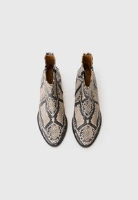 Botas de tobillo con estampado de piel de serpiente en beige y negro, con punta redonda y cremallera lateral para facilitar su uso. Interior de cuero suave.