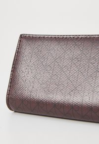 Textured brown leather wallet with a geometric pattern, featuring a smooth finish and rounded edges, showcasing detailed stitching.