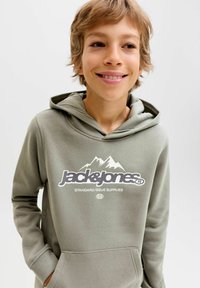 Olivno zelena kapuca iz mehkega materiala, z kengurujem žepom in natisnjenim logotipom z gorami, zasnovana za sproščeno nošenje.