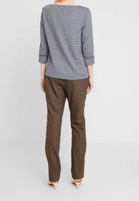 Svart och vit hounds-tooth mönstrad topp med trekvartslånga ärmar, tillsammans med bruna raka byxor och beige klackskor.