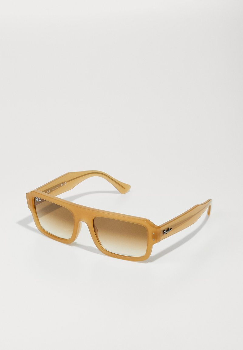 Ochelari de soare rectangulari cu un cadru transparent, de culoare chihlimbar. Lentile brune cu o nuanță gradient și temple proeminente cu un accent logo. Finisaj neted și lucios.