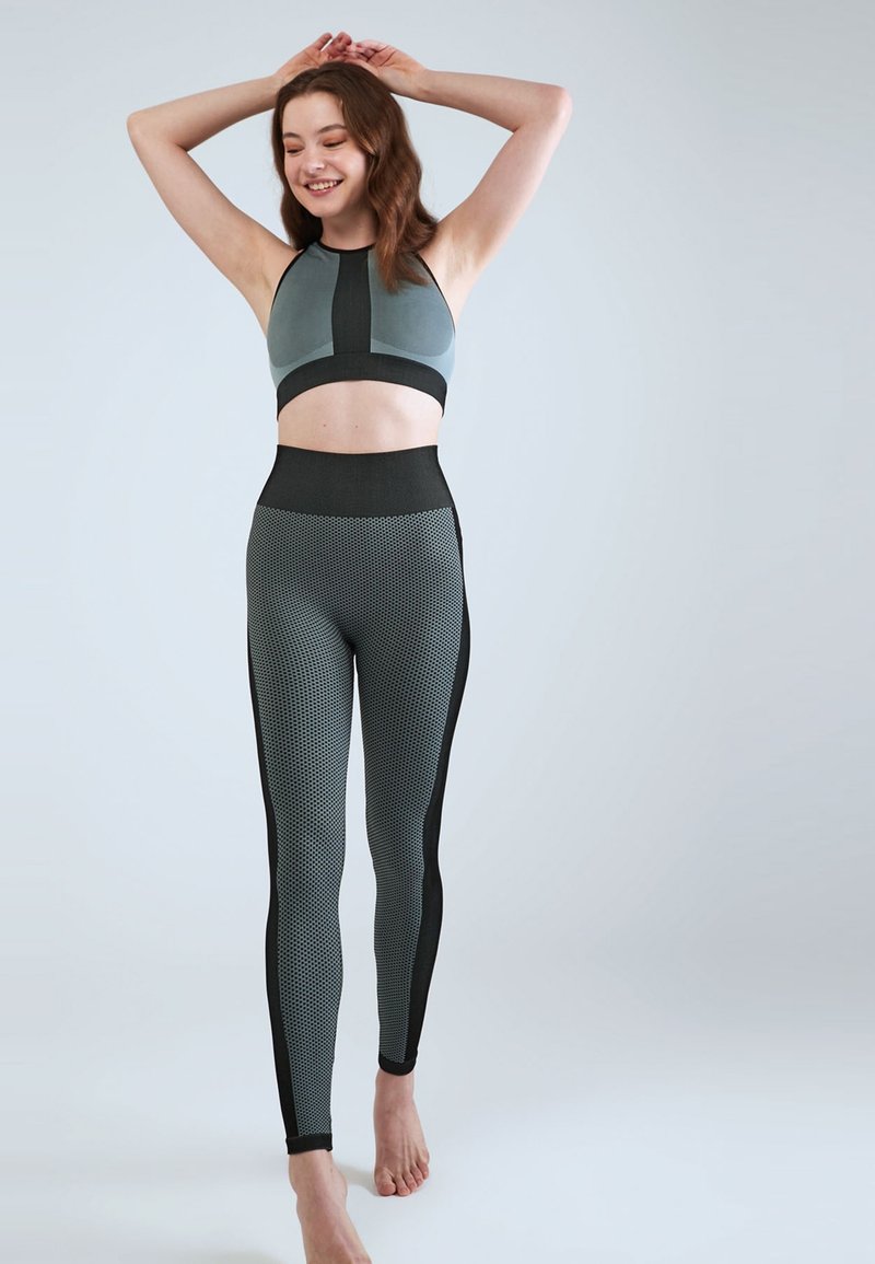 Sportbh och högmidjade leggings i teal och svart. Leggings har ett strukturerat mönster med nätpaneler längs sidorna.