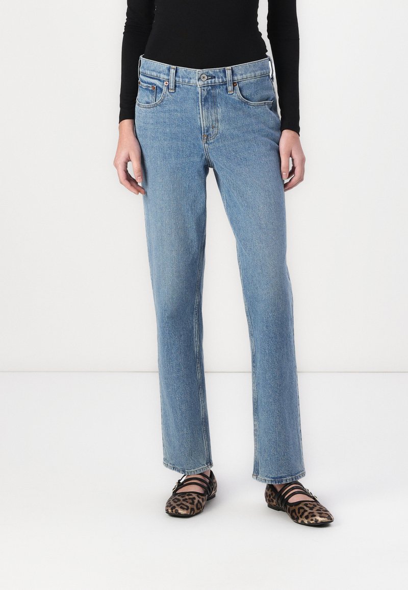 Light blue denim jeans with a straight fit and five-pocket design, featuring subtle stitching details and a classic button fly.