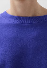 Paarse gebreide trui met een geribde ronde halslijn en een gladde textuur, nauw aansluitend rond de hals met geen zichtbare patronen of accenten.