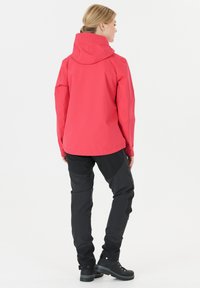 Red waterproof jacket with a hood, paired with black pants and sturdy black boots, featuring a fitted design and smooth texture.