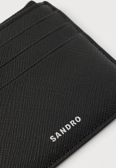 Μαύρη υφασμάτινη δερμάτινη θήκη καρτών με τρεις θήκες για κάρτες και την επιγραφή "SANDRO" σε λευκό, χαραγμένη στη γωνία στο κάτω μέρος.