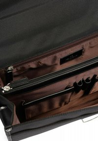Interno di borsa nera texturizzata con foderatura marrone, caratterizzato da scomparti con zip e molteplici tasche per organizzazione e stoccaggio.