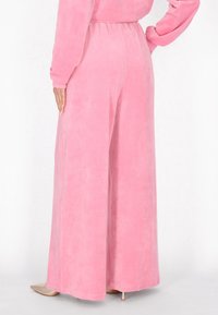 Roze wijde broeken gemaakt van zachte, gladde stof, met een elastische tailleband en een ontspannen pasvorm. Geen zichtbare patronen of hardware.