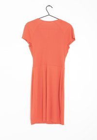 Robe à manches courtes en corail vif, faite en tissu léger, avec un corsage ajusté et une jupe évasée, suspendue à un crochet noir.