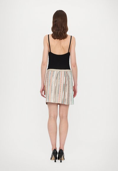 Black tank top with thin straps paired with a multicolored striped mini skirt. Visible texture and varying patterns, accentuated by heeled shoes.