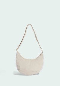 Bolso de hombro beige con forma curva, hecho de tela suave, que cuenta con una sola correa para el hombro y un diseño minimalista.