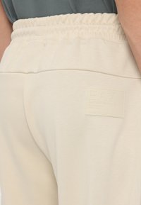 Crème kleurige sweatpants met een elastische tailleband, voorzien van een gestructureerde logo patch met verhoogde tekst op de achterzak.