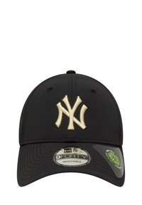 Gorra negra con un gran logo bordado en crema de 'NY'. Correa ajustable en la parte posterior, con una textura suave y visera redondeada.