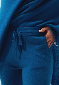 Blauwe fleece loungestijl set met een ontspannen pasvorm, verstelbare tailleband en zijzakken. Zachte textuur met een gladde afwerking, ideaal voor comfort.