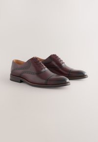 Chaussures habillées en cuir marron avec bout droit, détails en brogue et section d'orteil noire contrastante. Talon plat et design à lacets.