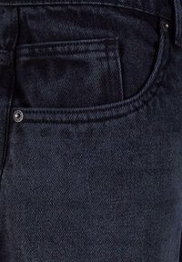 Dark denim jeans featuring a textured surface, standard pockets, and a metal button on the front pocket's edge.