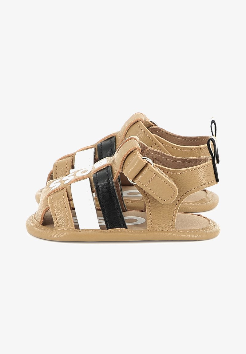 Tan leather sandals with black and white stripes, open-toe design, adjustable buckle strap, and a textured sole. Accents include a logo detail.