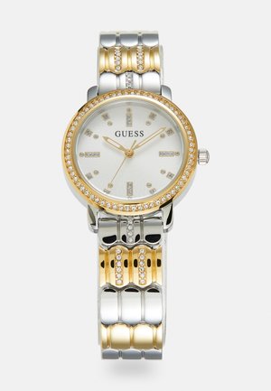 Gold and silver metal watch with a round face, crystal accents, a white dial, and a patterned link bracelet. Brand name "GUESS" displayed.