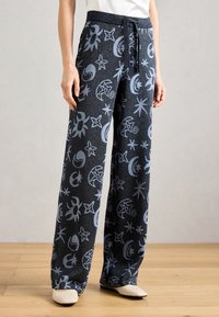 Pantalons à jambes larges en tissu bleu marine avec des motifs célestes bleu clair, comprenant des étoiles et des lunes, dotés d'une taille élastique et d'un cordon de serrage.