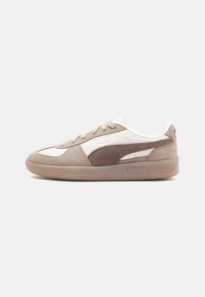 Tan og beige sneakers med overdel i ruskind og læder, rund tå, snørelukning foran og en gennemsigtig sål med PUMA-branding.