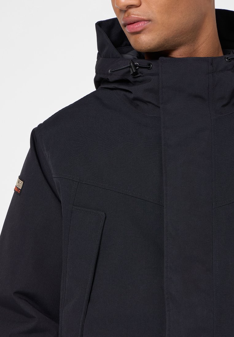 Veste à capuche noire en tissu texturé, fermeture éclair à l'avant et poche poitrine. Elle dispose d'une capuche ajustable et d'une étiquette de marque discrète sur la manche.