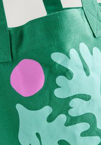 Groene canvas tas met een gestructureerd oppervlak, met een grote roze cirkel en lichtgroene abstracte vormen. Stevige handgreep.