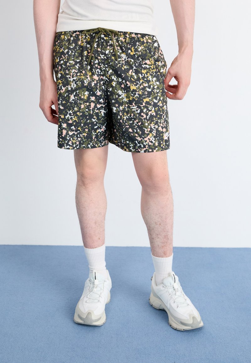 Patterned swim shorts in dark green, featuring a mix of pink, yellow, and white speckles. Elastic waistband with drawstring detail.