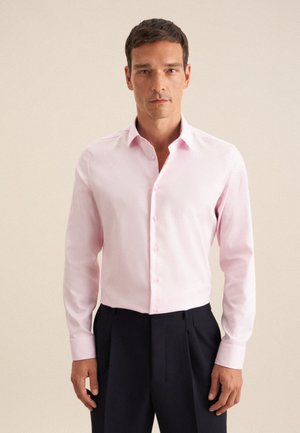 Light pink button-up shirt with a classic collar, long sleeves, and smooth texture, paired with dark trousers.
