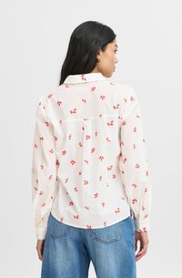 Cămașă albă cu mâneci lungi, cu model de frunze roșii, cu manșete butonate și detaliu de yoke pe spate. Fabricată dintr-un material ușor, cu un croi lejer.