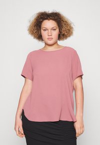 Rosa farget kortermet bluse med rund hals, avslappet passform og sidedeler, laget av et teksturert stoff. Kombinert med et svart skjørt.
