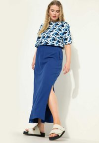 Blauwe lange rok met een zijsplit, gecombineerd met een witte en blauwe bloempatronen top. Draagt bij chunky crèmekleurige sandalen. Glad materiaal, casual ontwerp.