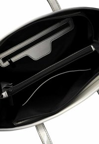 Sandyfarbene Tote-Tasche mit schwarzem Stoff-Futter im Inneren, ausgestattet mit mehreren Taschen, einem Reißverschlussfach und einer glatten Oberfläche.