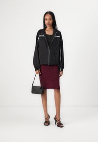 Black zip-up jacket with embroidery, black tank top, burgundy textured pencil skirt, black crossbody bag, and black strappy high-heeled sandals.