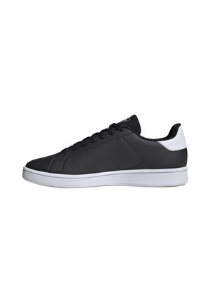 Zapatilla negra de corte bajo con suela y parche del talón blancos, cordones negros y parte superior de cuero texturizado, mostrada de perfil sobre un fondo blanco.