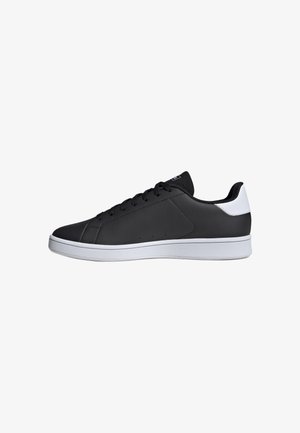 Niskie czarne sneakersy z białą podeszwą i tylną łatą, czarne sznurówki oraz skórzana górna część o teksturowanej powierzchni, pokazane z boku na białym tle.