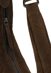 Hnědá semišová taška s černým zipem a texturovaným popruhem. Design zdůrazňuje hladký povrch a pevné kovové doplňky.