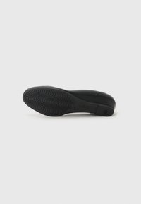 Scarpa flat nera con tomaia liscia, forma curvata e suola in gomma testurizzata con un motivo ondulato per una migliore aderenza.