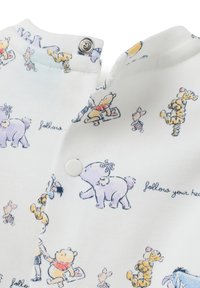 Tela blanca con personajes en tonos pastel de Winnie the Pooh, incluyendo a Pooh, Piglet, Tigger y Eeyore, con detalles de botones a presión y el texto "sigue tu corazón".